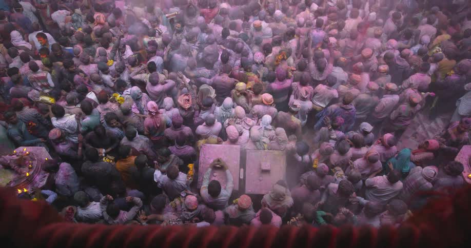 Over a balcony people are standing in a crowd below