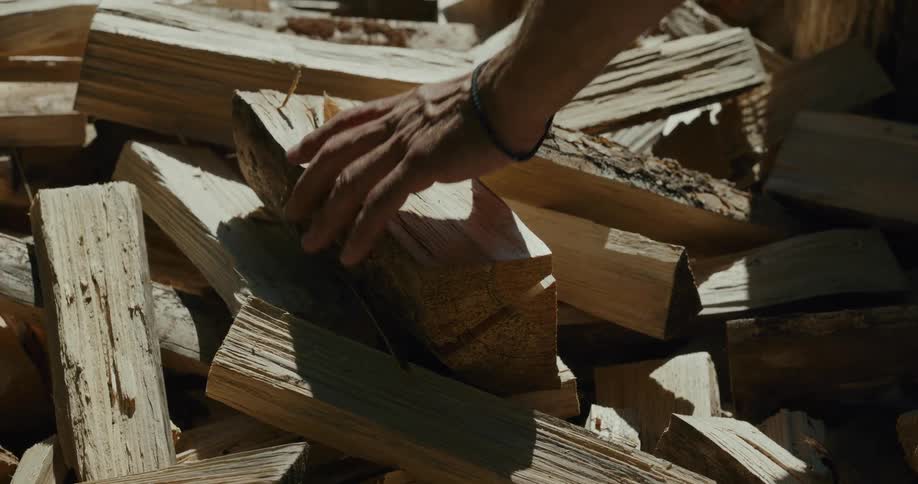 A man lifts up a piece of chopped wood