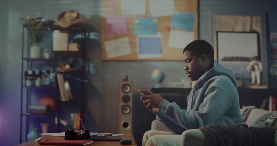 Young man sitting on a couch at home answers a call on his smartphone