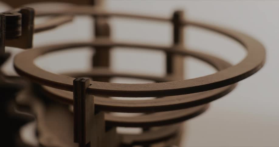 A gear moves a marble down a spiral funnel
