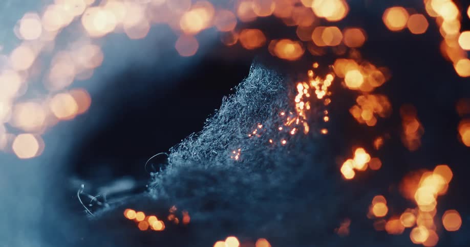 A fibrous material slowly burns as sparks flicker and then fall or extinguish themselves