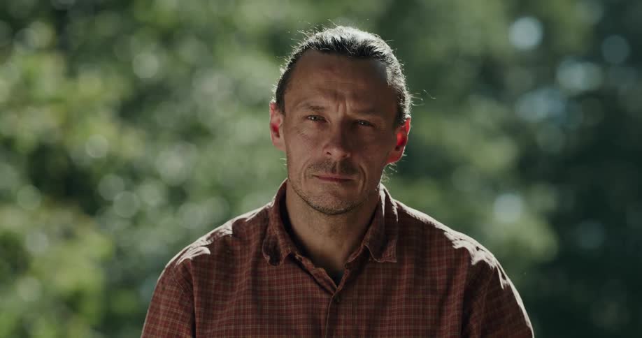 A man is sitting outside near some trees