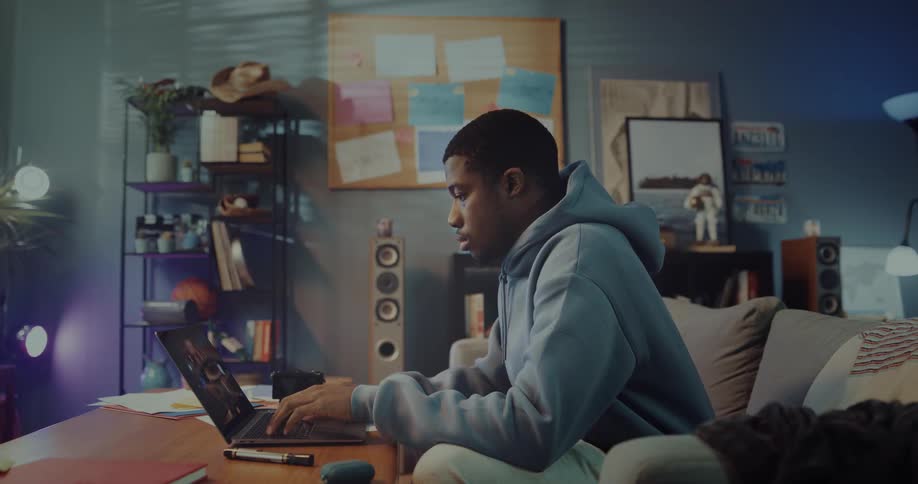 A man sits on a couch and sets his laptop computer on the table and types on the keyboard