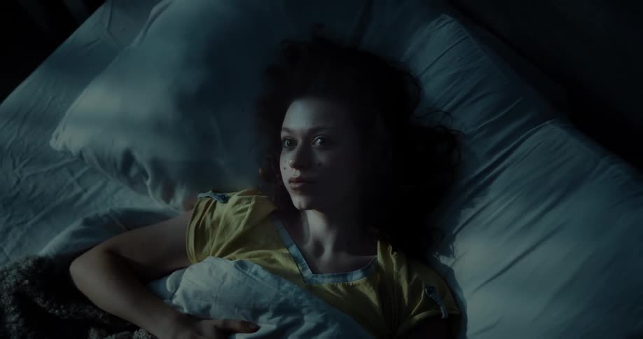 A young woman lies in bed while lost in thought at night