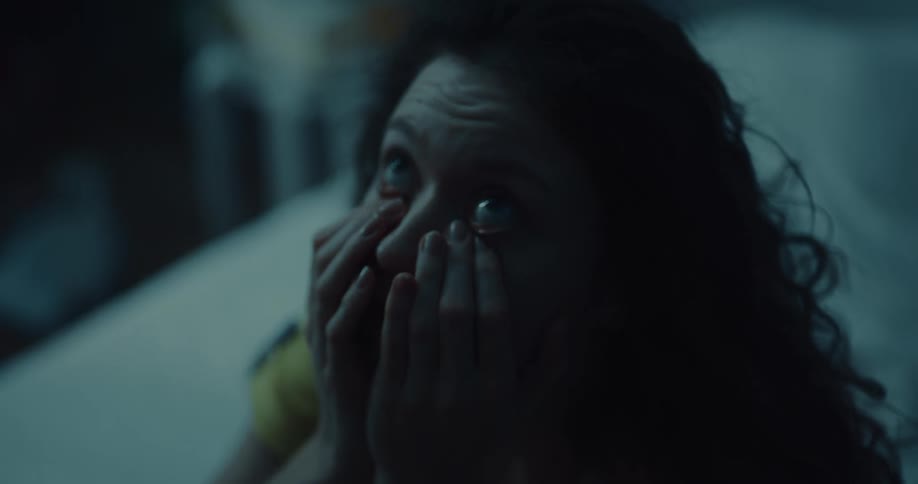 Young woman laying in bed wakes up and looks at the ceiling while rubbing her face