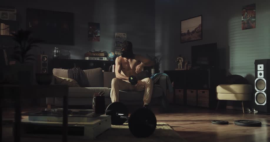 Young man sitting on a couch at home works out while wearing vr goggles