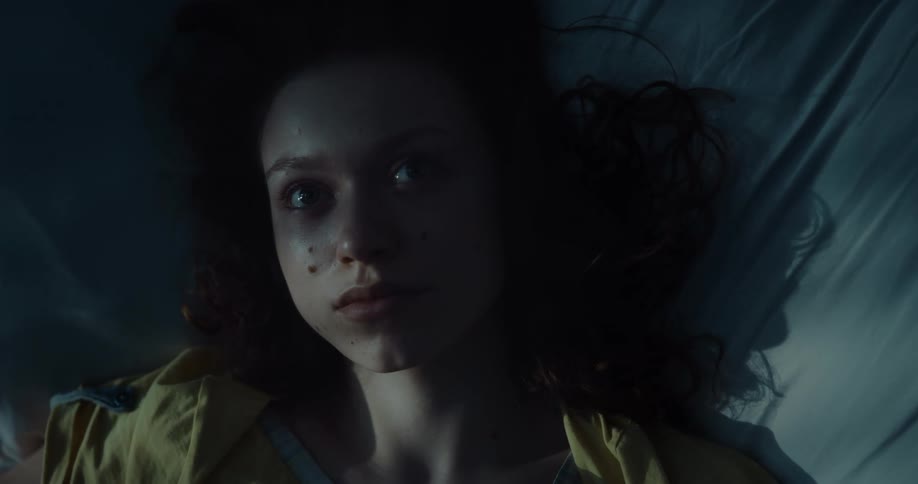 Young woman laying in bed at night looking at the ceiling instead of sleeping