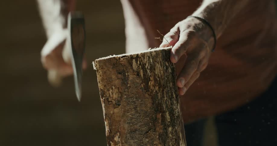 Man uses hatchet to split wood