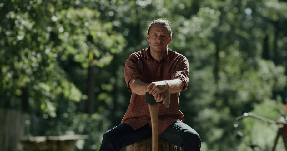 A man is sitting on a log with an ax