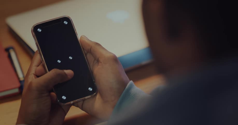 A man uses his smartphone while sitting at a desk