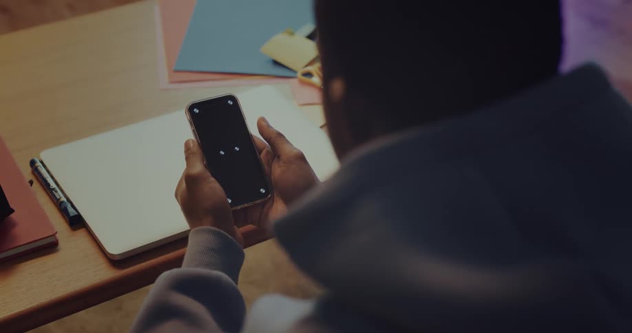 A man is sitting at a desk using his cell phone