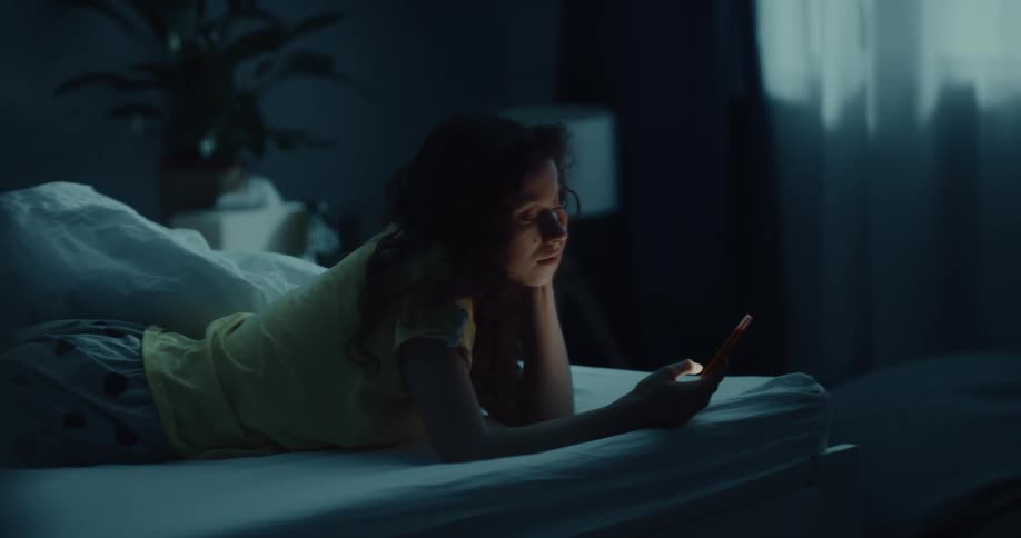 A woman is using her phone in bed