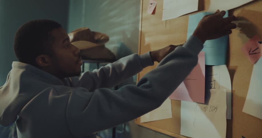 Young man organizes documents on a billboard at home