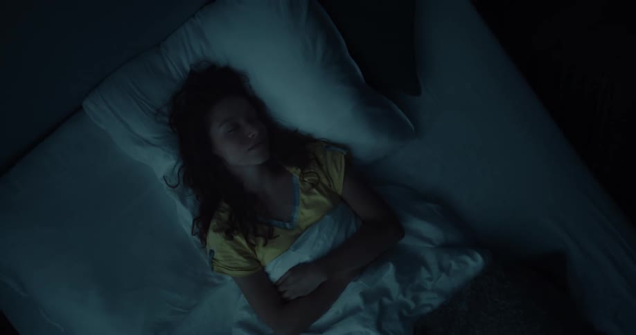 A woman lies back in bed and closes her eyes