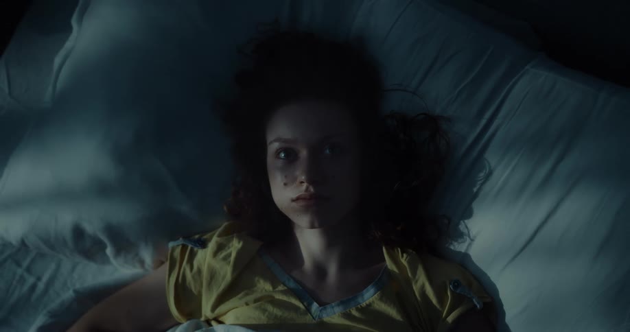 A woman asleep in bed opens her eyes and stares straight up