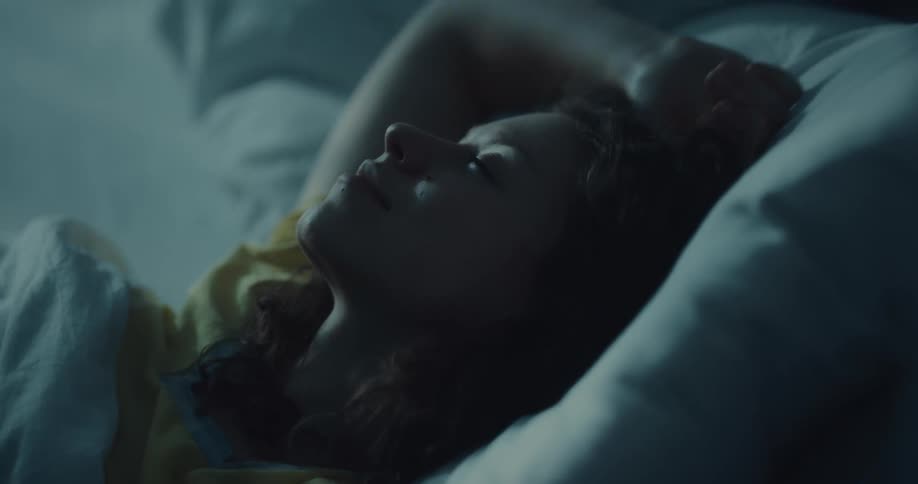 Young woman sleeping in her bedroom turns around in the bed