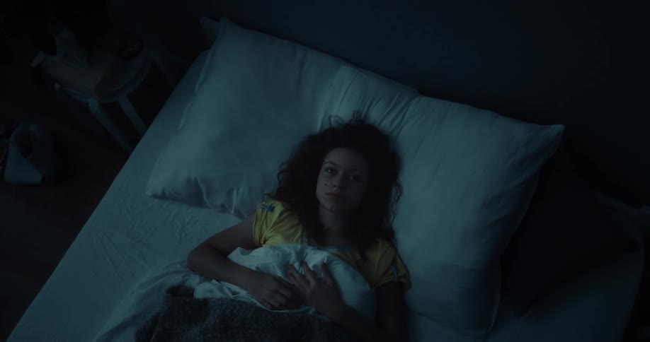 A woman fidgets and stares up at the ceiling while resting in bed