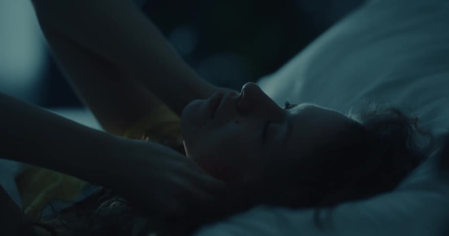 A woman reaches for the ear plugs on her night stand puts them in and lies back down