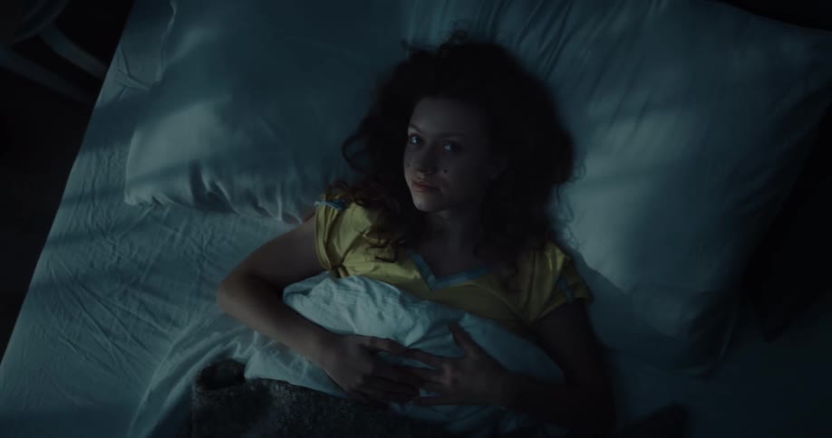 Young woman laying in bed at night looking at the ceiling instead of sleeping
