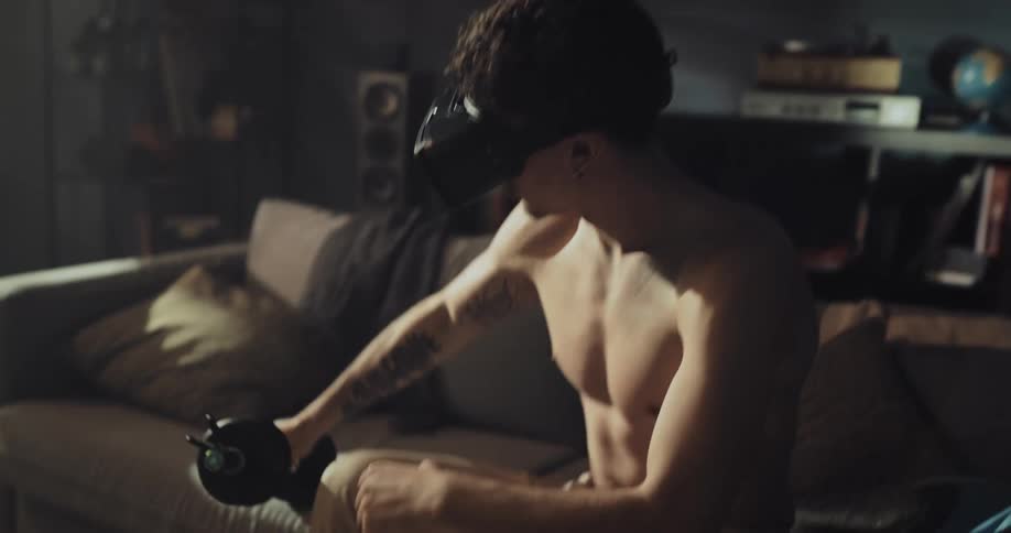 A young man puts on a virtual reality headset an then begins to lift a weight