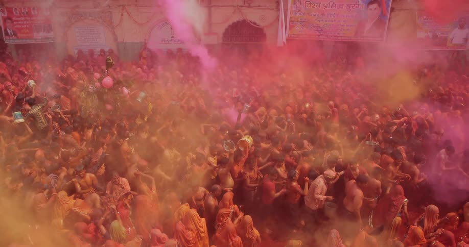 People are celebrating below surrounded by colored dirt in the air