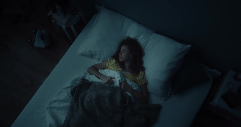 Young woman tossing and turning in her bed trying to sleep at night