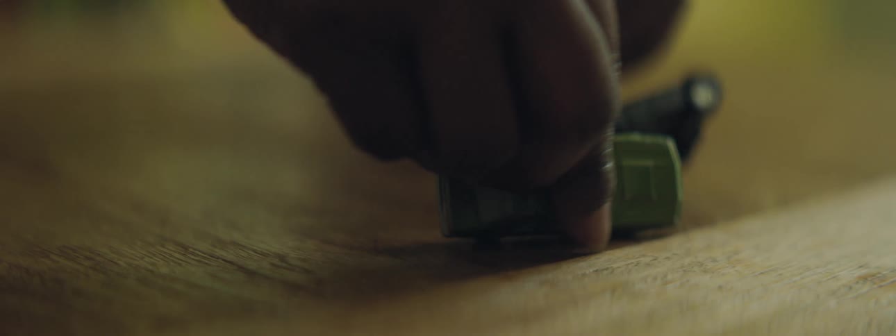 Person manuevers toy cars across wooden floor crashing them into each other