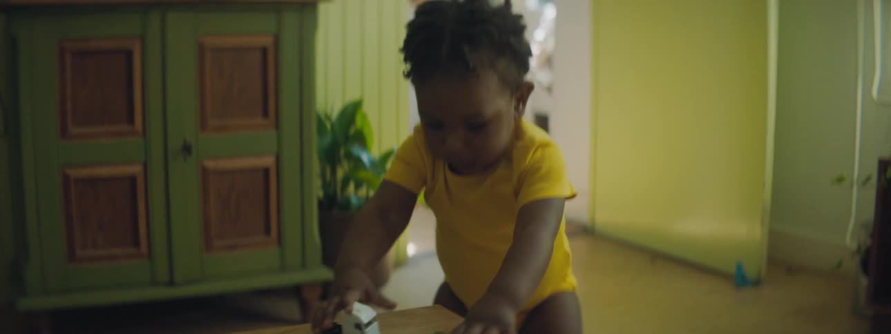 A person directs a toddler to toy cars on a table with their finger