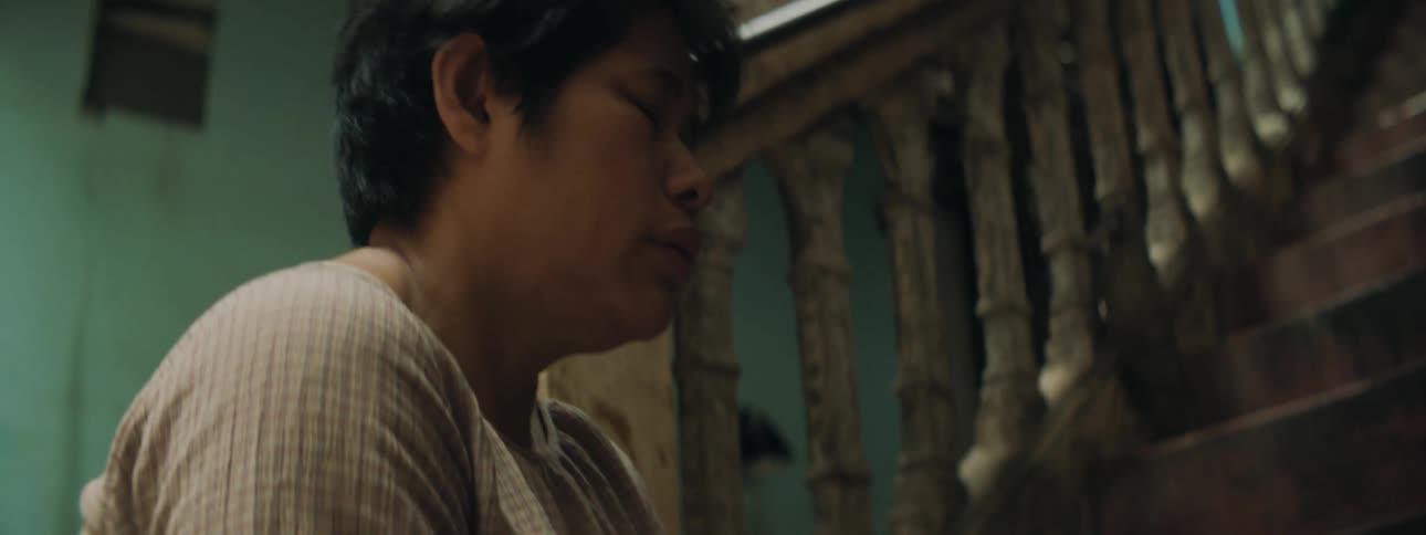 A woman rubs a mans hand as he lies at the bottom of a set of stairs bleeding