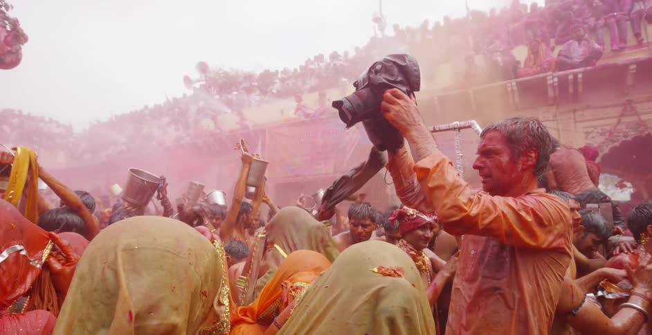 A man lifts a camera above a crowd filming them