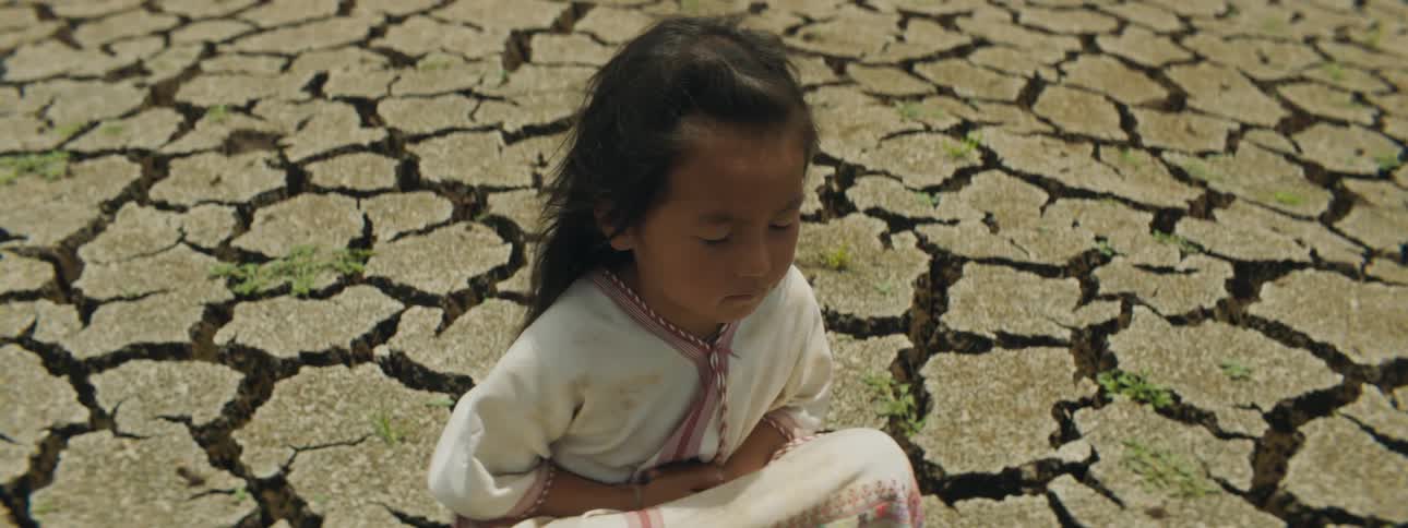 A young child sitting on the ground with her eyes closed