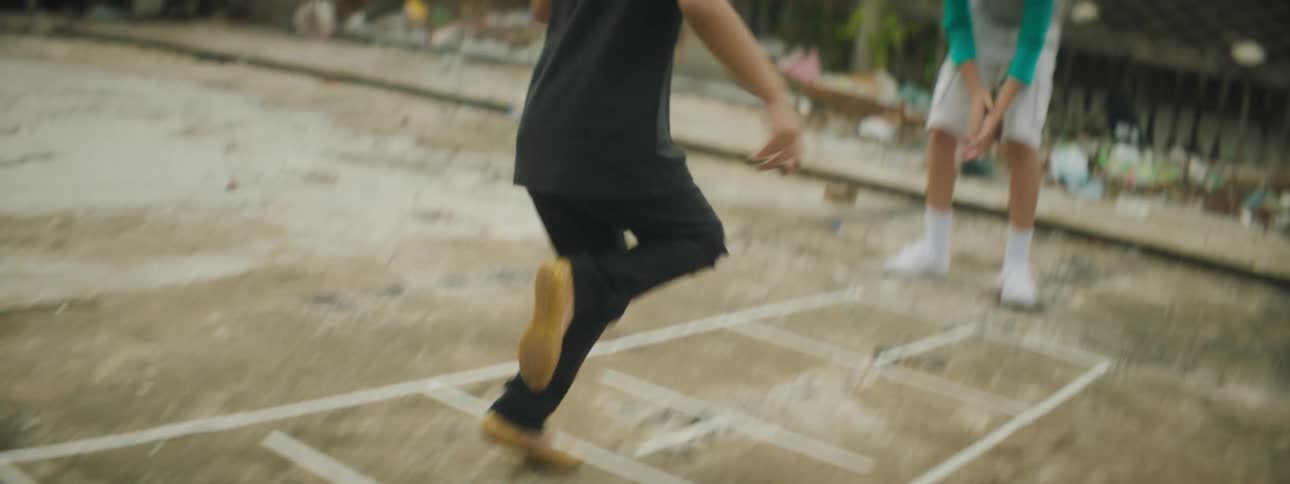 A young girl skips across a hopscotch in a dirty third world location