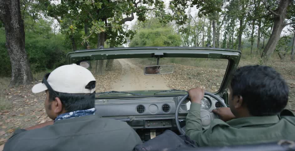 Two men riding in a car down a dirt road