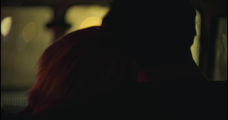 A man and woman cuddle in a car at night