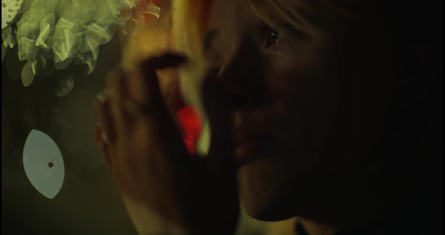 A woman sits in a car at night and wipes her tears.