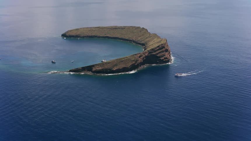 An aerial view of boats in the ocean by an island