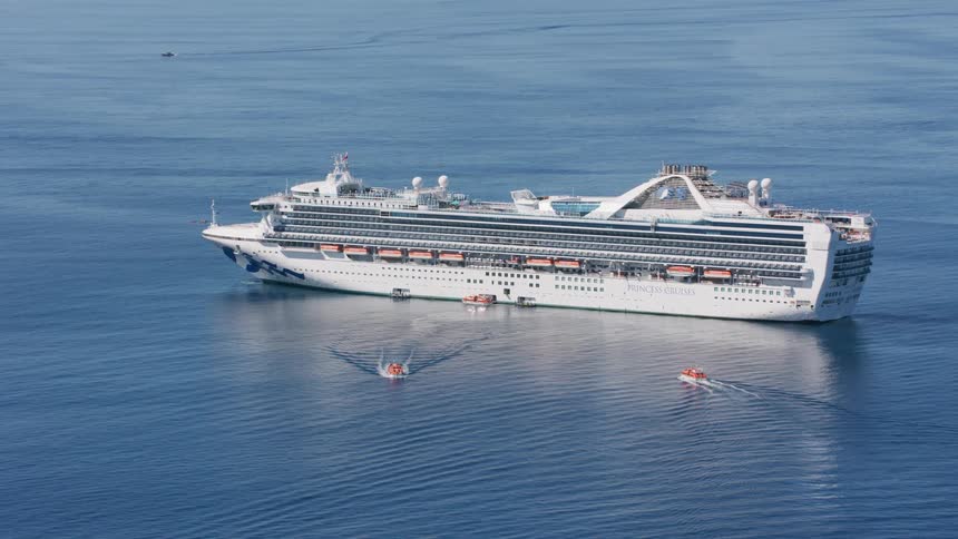 Supply boats traveling to and from a princess cruise ship in the ocean