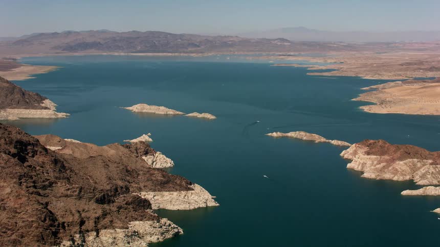 Small boats sail in deep blue water among islands and surrounded by mountains