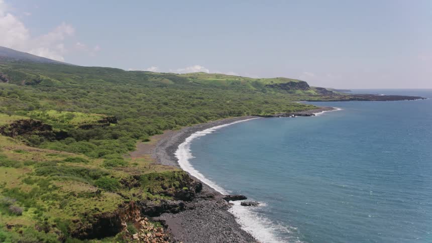 Land slopes from top of misty mountains to meet the crashing waves on the shore