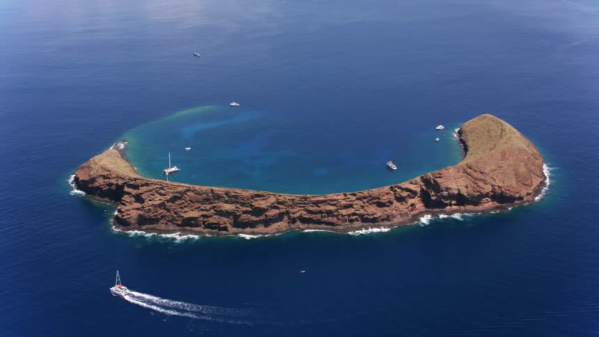 An aerial view of boats by an island in the ocean