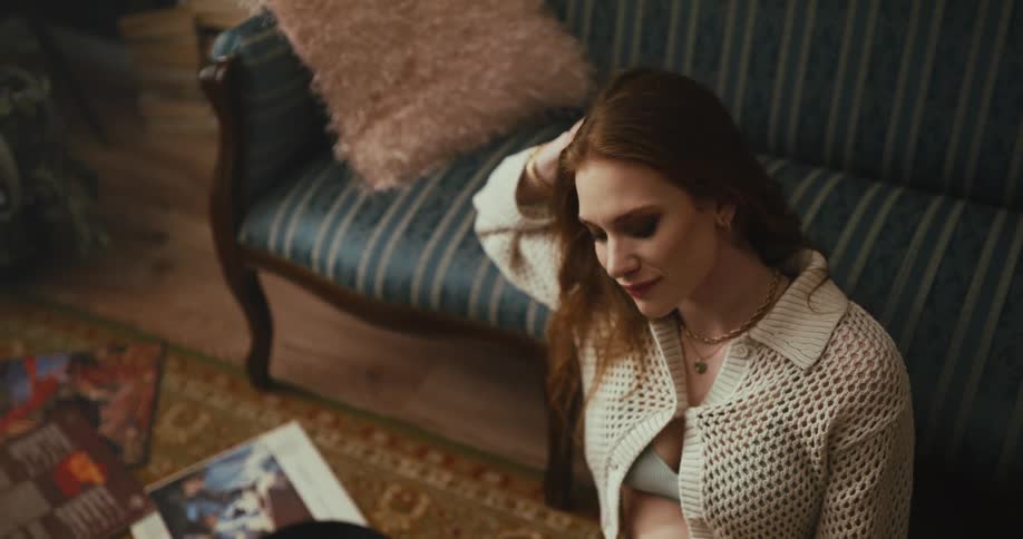 A woman leaning back against the couch while sitting on the floor listening to music
