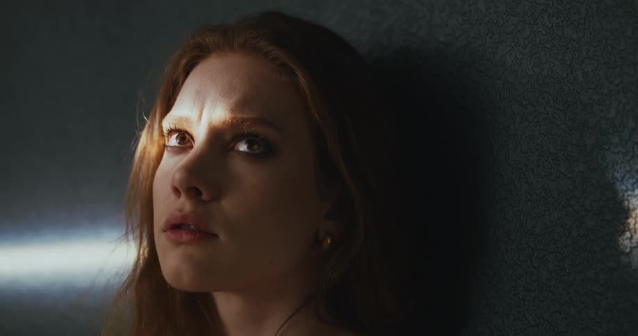 Sunlight shines on a womans face while she leans against a wall