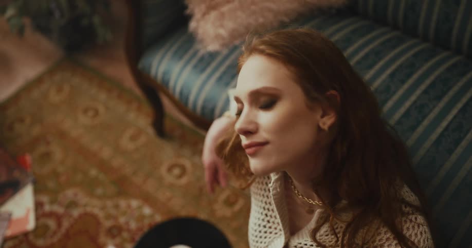 A woman sitting on the floor tapping her foot and swaying to the music