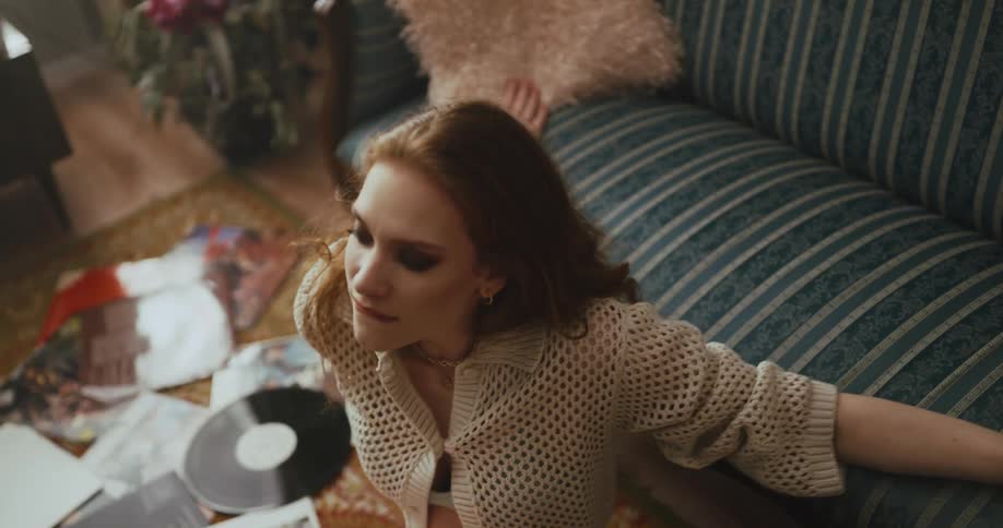 A woman dances while sitting on the floor and listening to vinyl records
