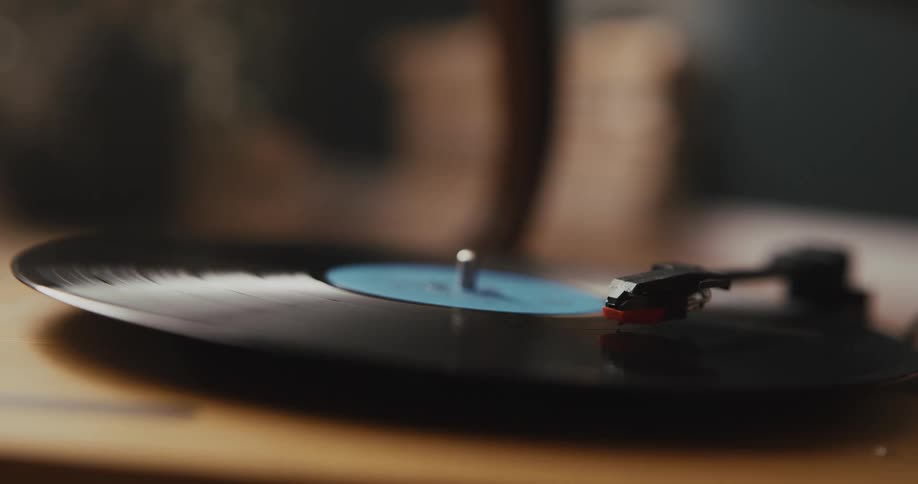 A person puts a needle on a record on a vintage record player