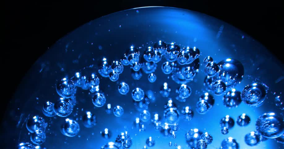 Multiple small bubbles are embedded within an blue glass sphere that is rotating