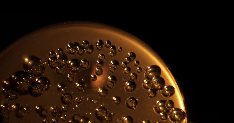 Small bubbles are embedded within an amber sphere made of glass