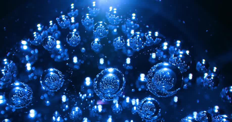 A spinning glass ball with air bubbles shimmers and glows in blue