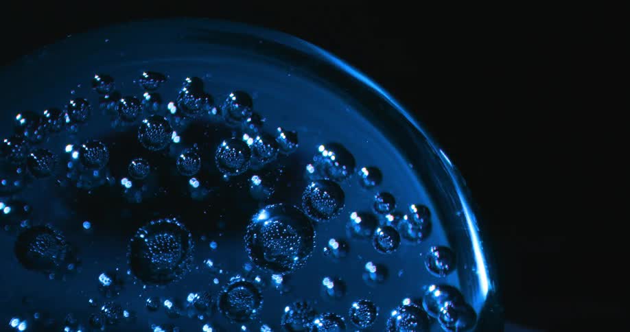 Numerous bubbles are enclosed within an blue glass sphere that is rotating