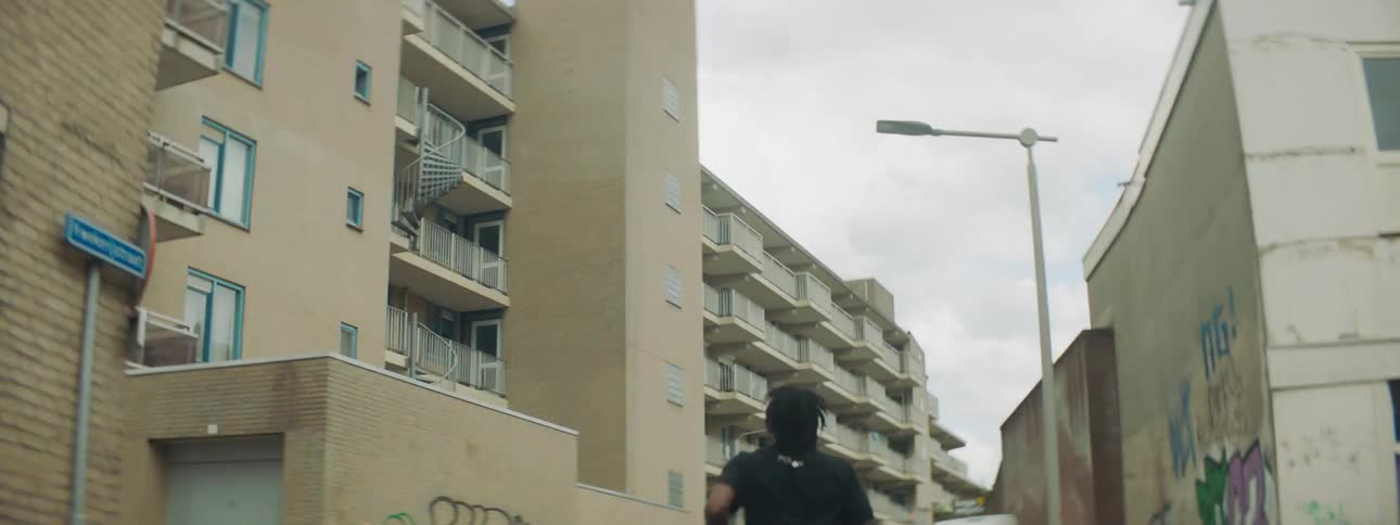 A man sprints through an alley running between apartment buildings in a city